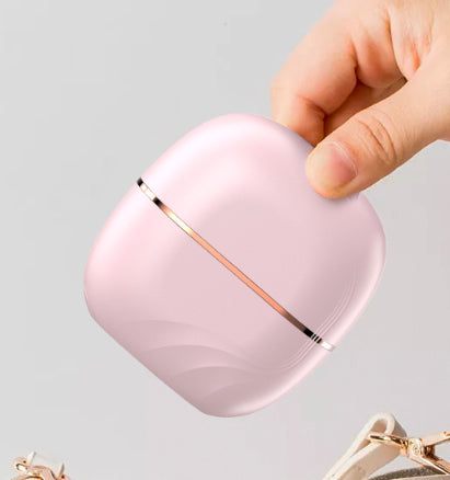 The pink comb held in one hand with its lid on